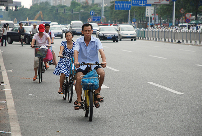 Scene from Chinese city with people riding along the road on bicycles, Dongguan