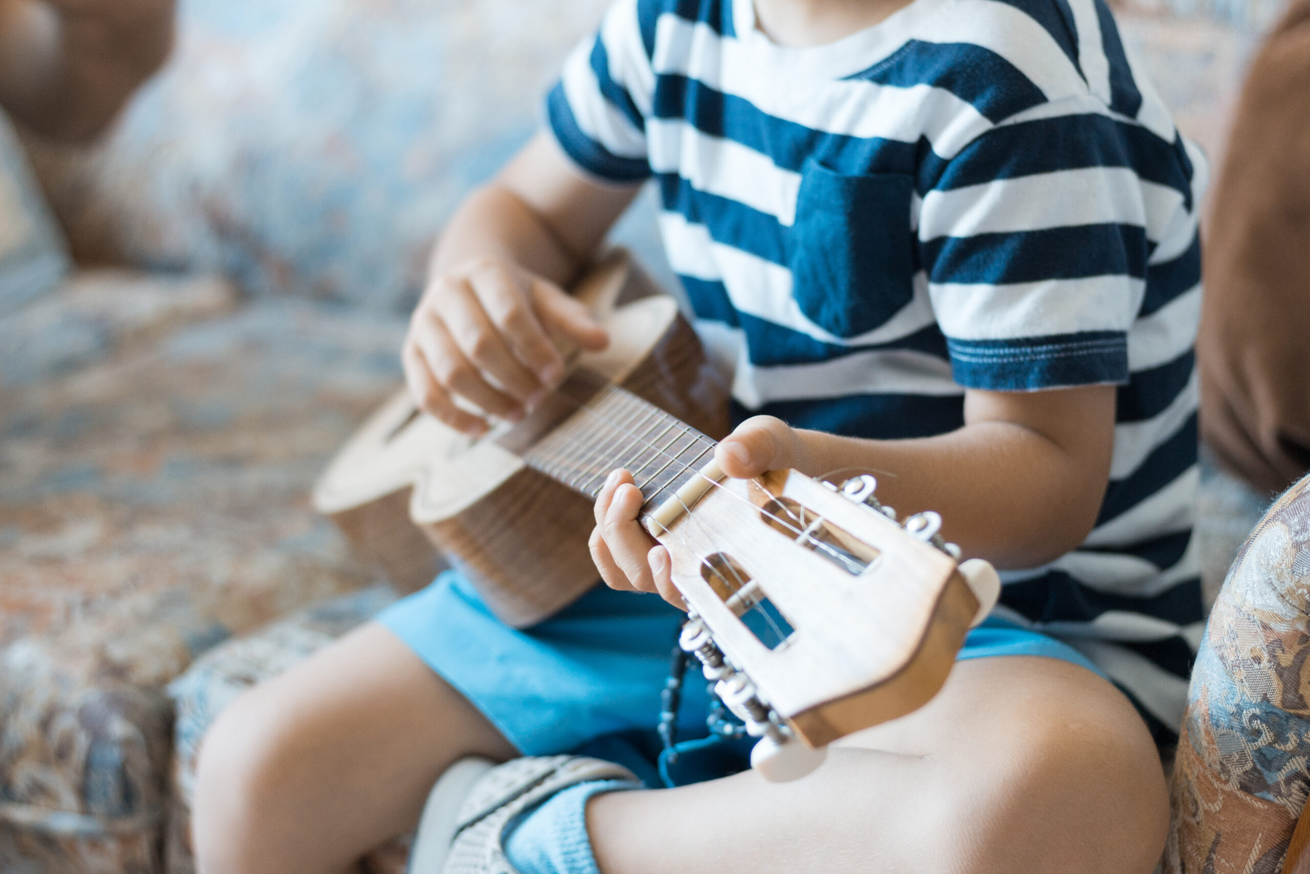 Caucasian,Child,Playing,And,Making,Music,Chords,With,Small,Guitar